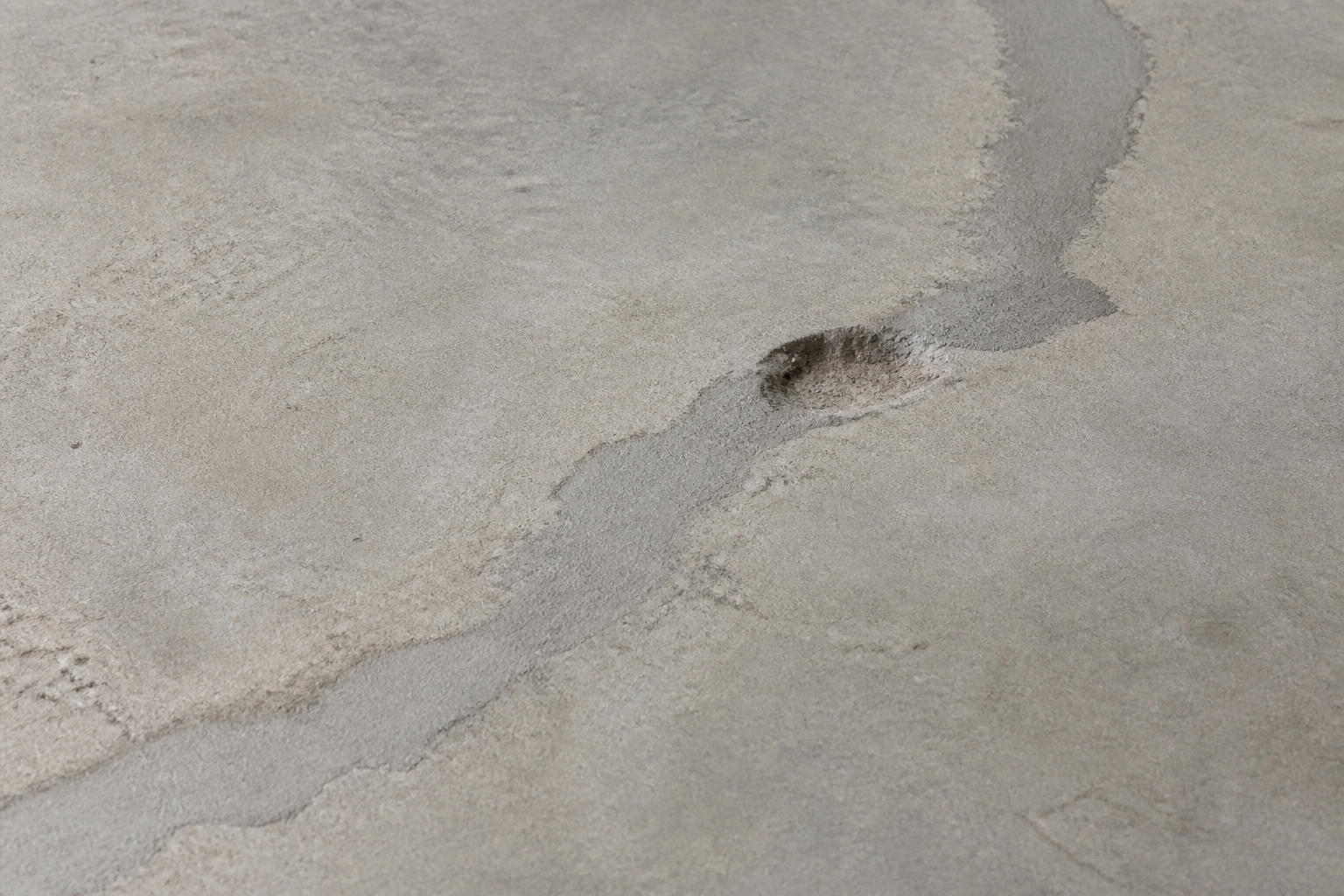 Repaired crack and small spall on a concrete slab before coating